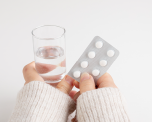 錠剤と水の入ったコップを手にしている様子